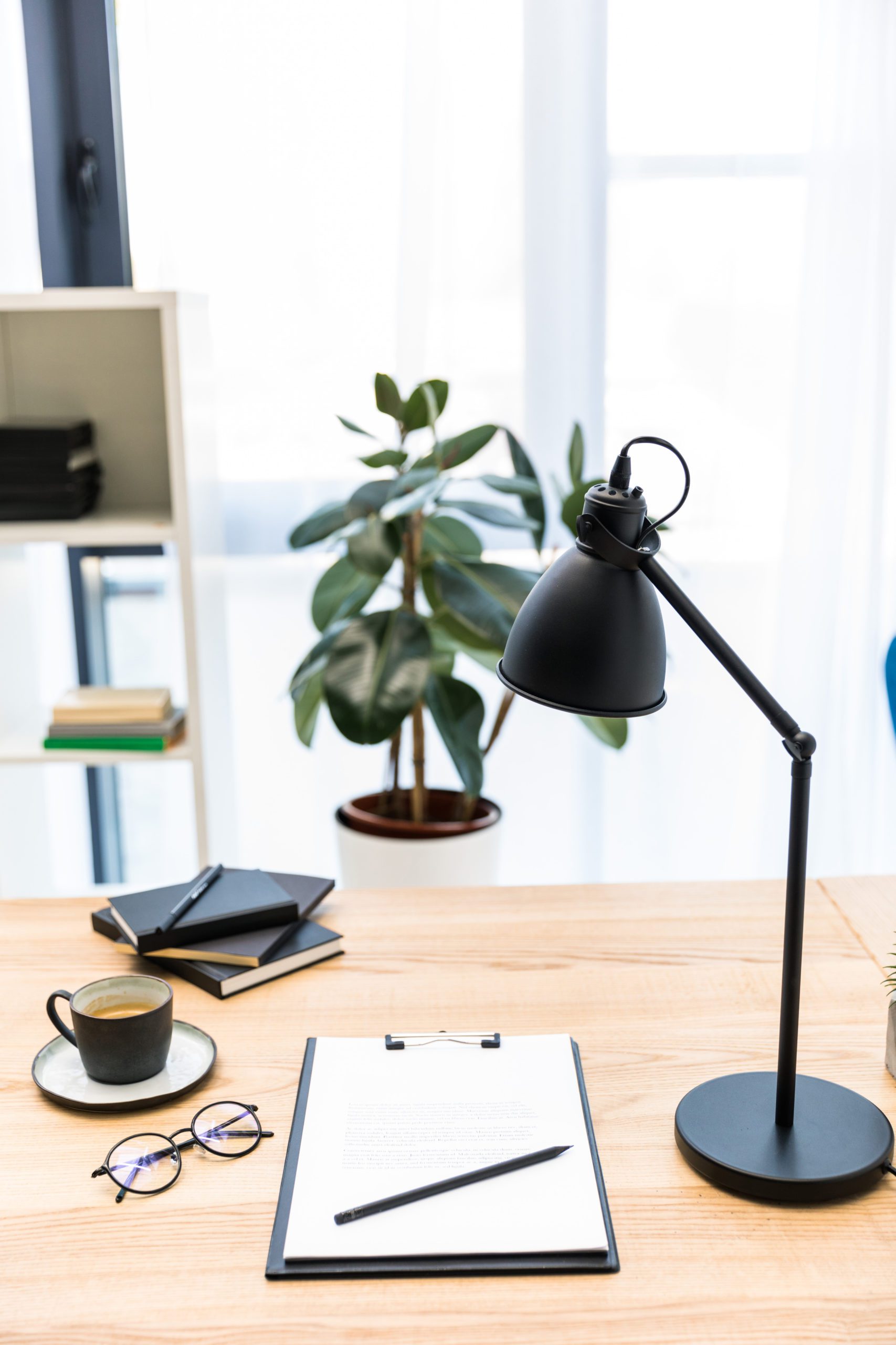 close up view of cup of coffee, eyeglasses, documents and lamp at workplace in office